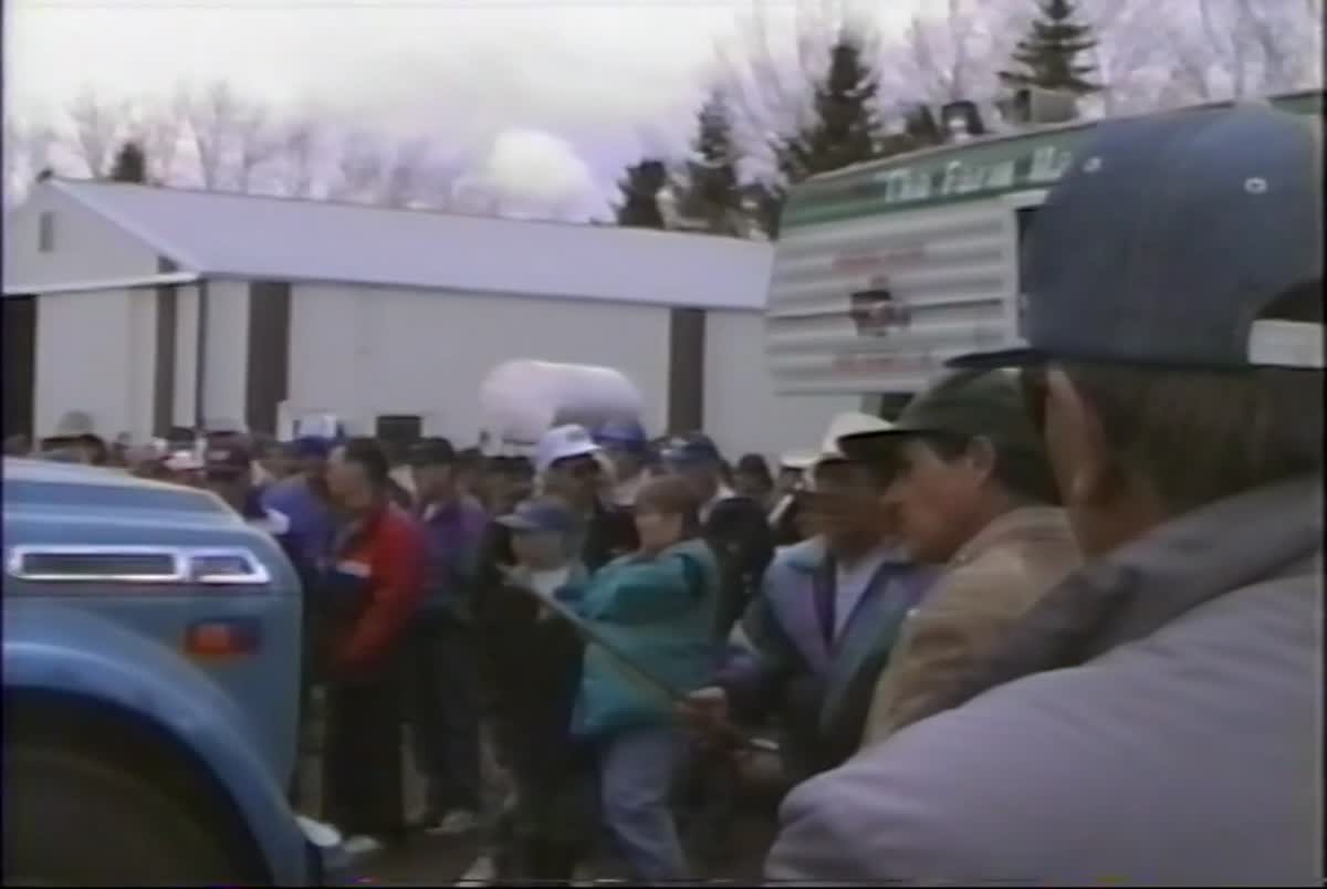 The auction crowd in caps and spring jackets, pressed close around the goods on sale day, April 27, 1996
