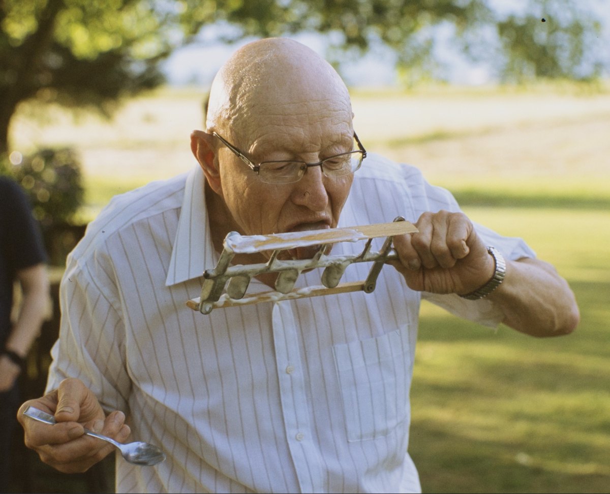 Walter outdoors on a summer day, happily licking homemade ice cream straight off the wooden dasher, spoon at the ready in his other hand